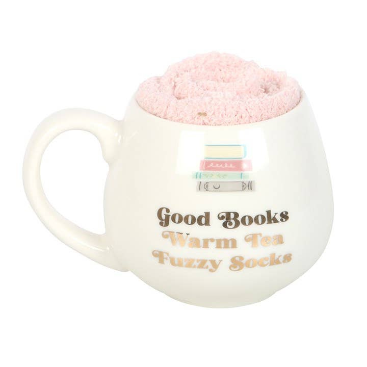 White mug with pink interior, text 'Good Books Warm Tea Fuzzy Socks', and a small pink fuzzy ball on a white background.