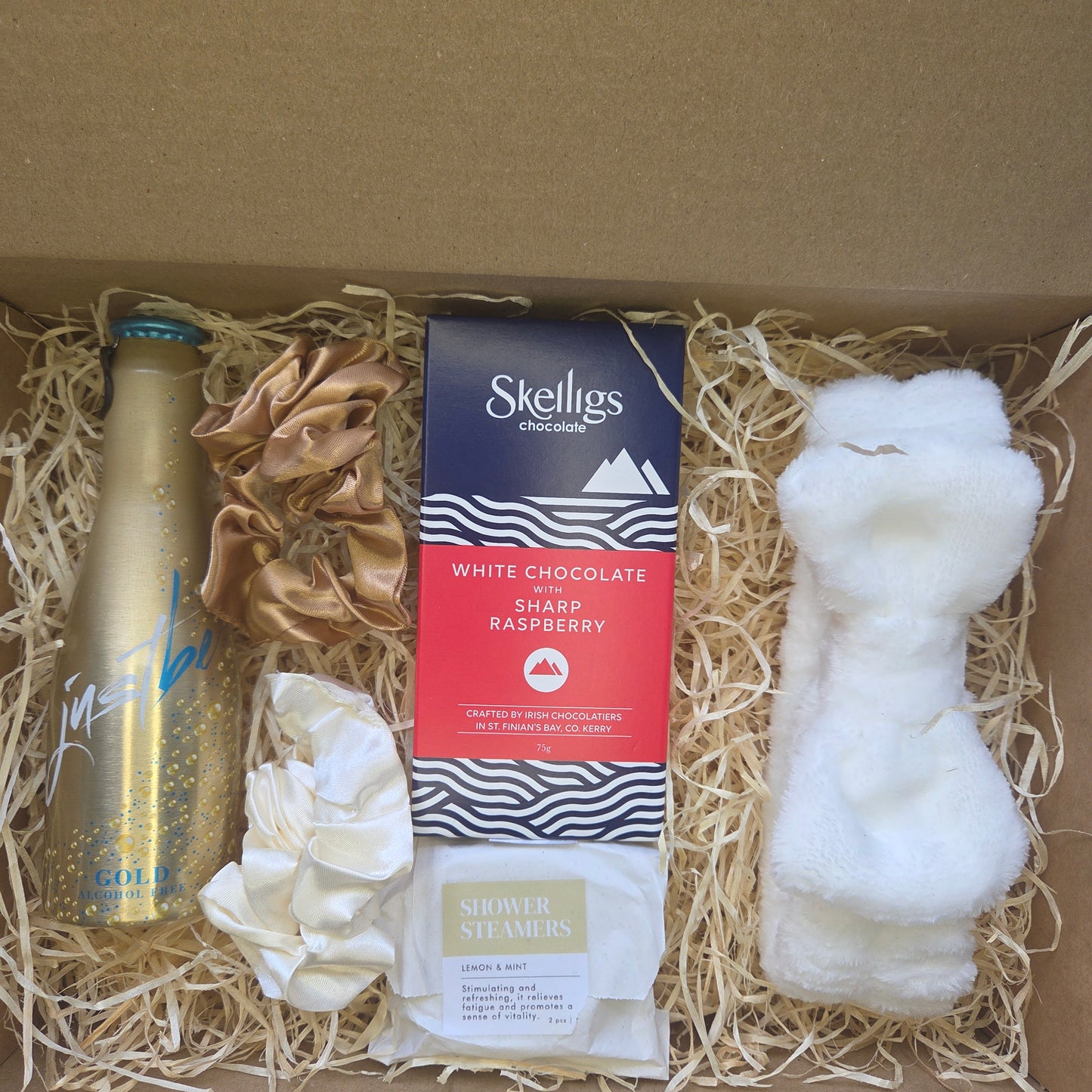 Gift box with Stellies chocolate, a bottle, and other items on straw