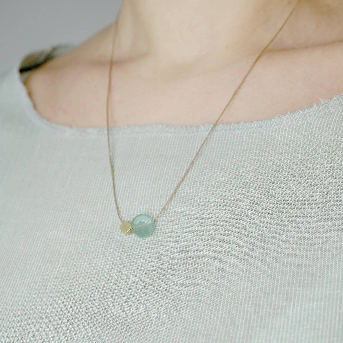 Necklace with a green pendant on a light gray background