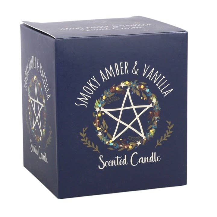 A dark blue square box for a scented candle, featuring a white pentagram inside a floral wreath and the text 'SMOKY AMBER & VANILLA' and 'Scented Candle'.
