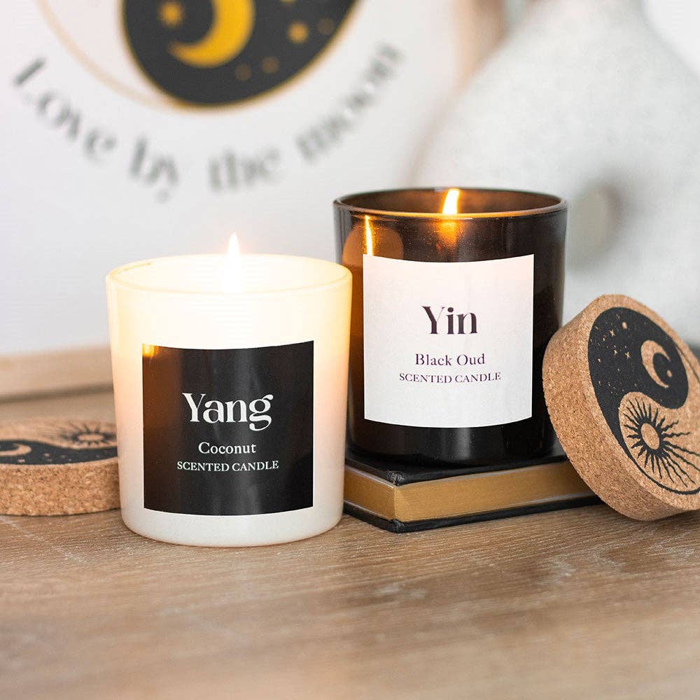 Two scented candles labeled 'Yang' and 'Yin' on a wooden surface.